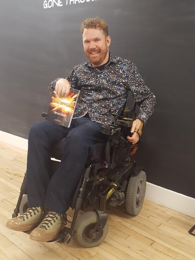 Luke Anderson, smiling and holding up a copy of Unstoppable, the book he co-authored.